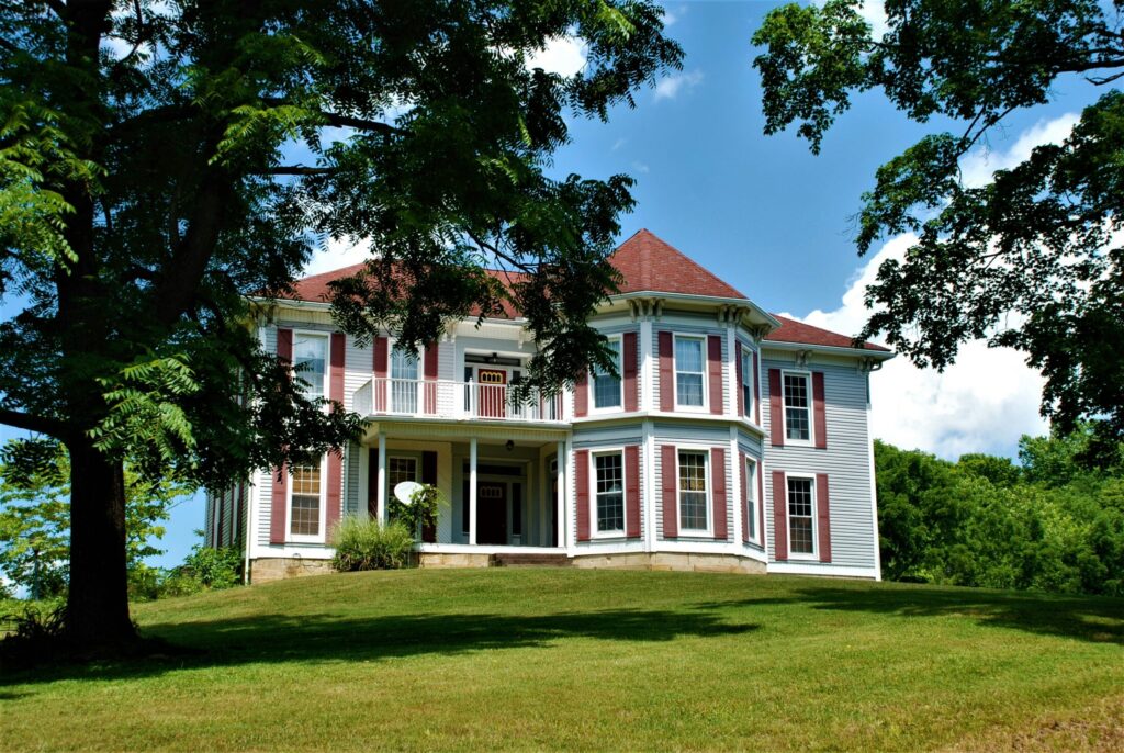 white and brown wooden house near green trees under blue sky